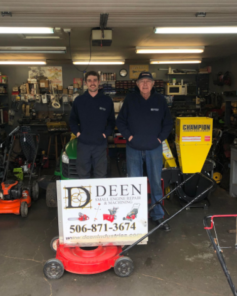 Two men standing inside small engine repair shop