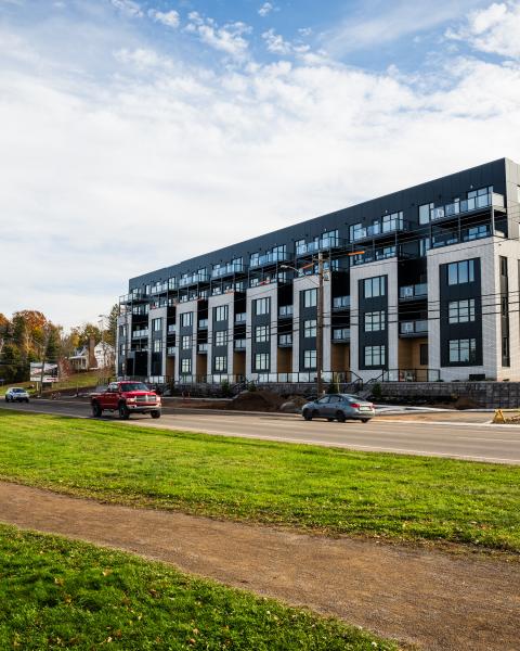 two people walk on riverfront trail with apartment in background
