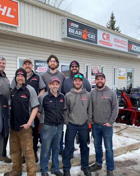 9 male team members stand outside cr yardworks and equipment in winter