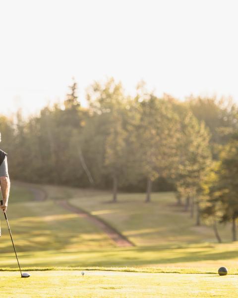 Older man waves at sunrise at golf course