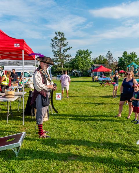 Vendors set up outside at a park with kids playing