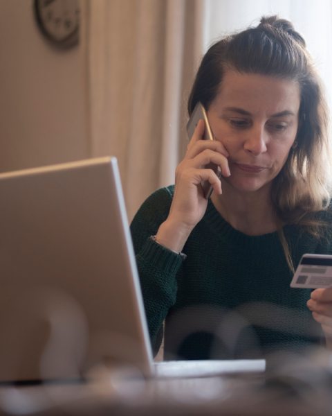 woman holding credit card while on the phone