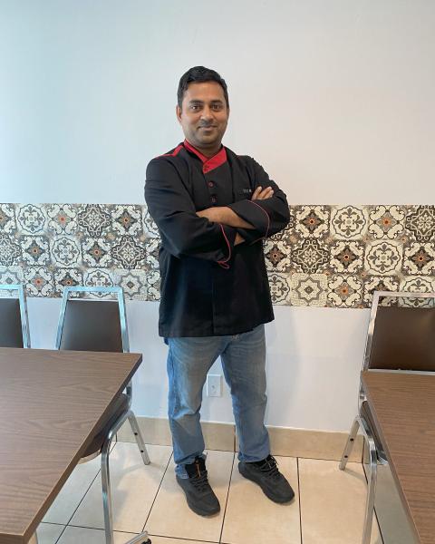 Restaurant owner smiling in store with arms crossed
