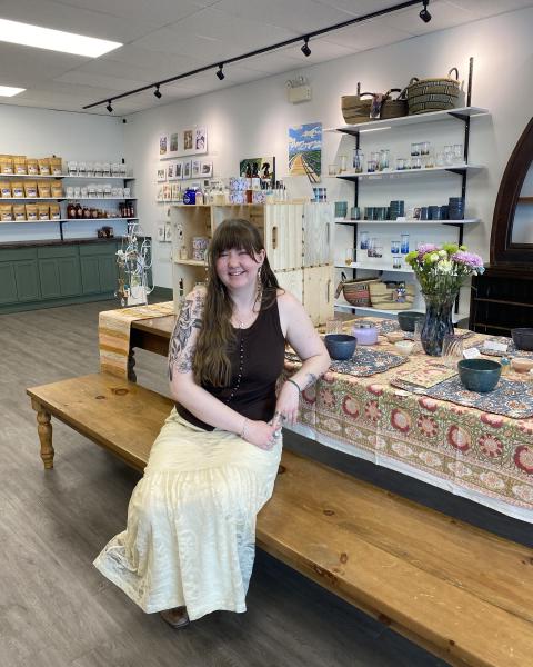 Fine craft store owner sitting at a display table, smiling