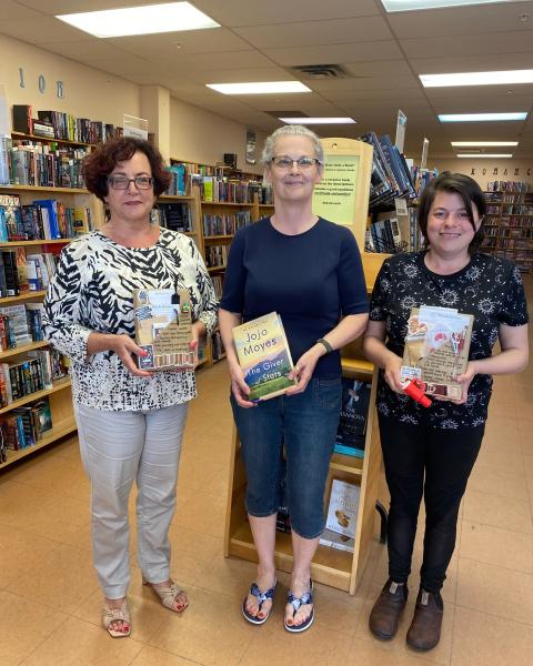 Crystal at Cover to Cover standing with her coworkers, smiling and holding books