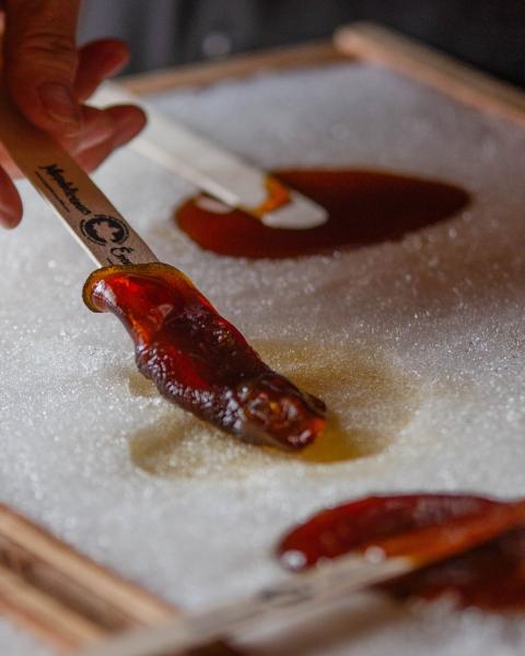 Someone dipping popsicle stick in maple taffy on the snow