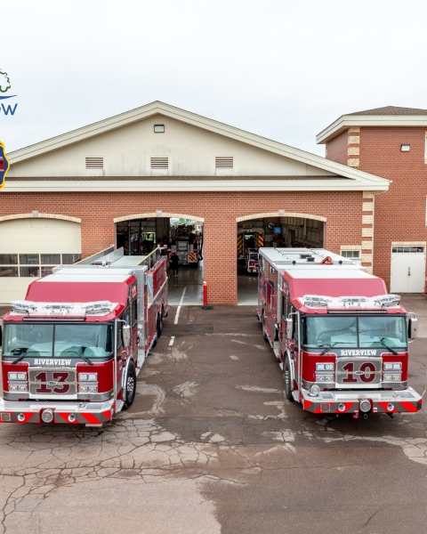 Two new firetrucks in front of bay doors of fire station