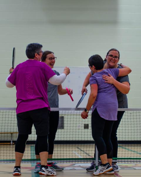 Two teams hugging over pickleball net