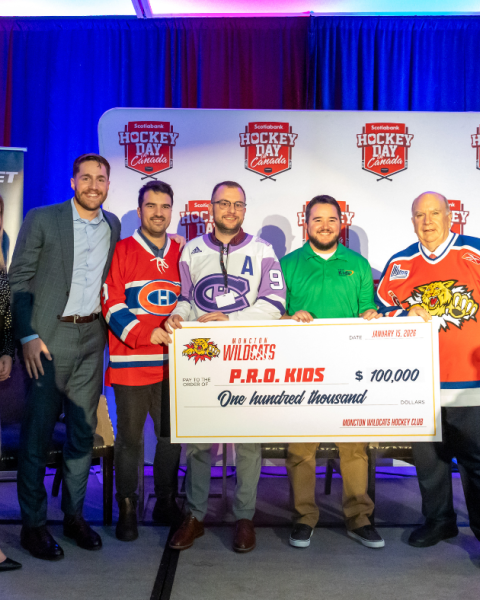 Group of people smiling and holding a large ceremonial cheque at a presentation event.