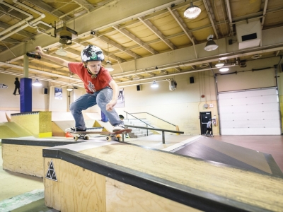 Young person wearing a helmet while riding down an indoor skateboard ramp